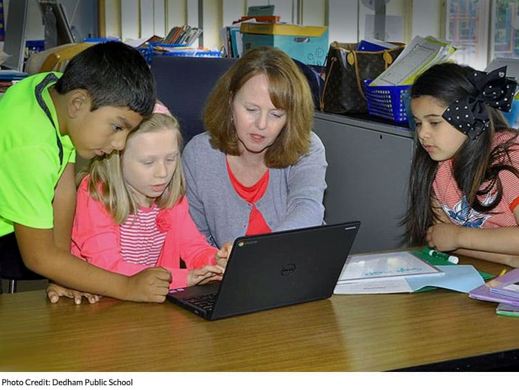 Teacher with students looking at laptop