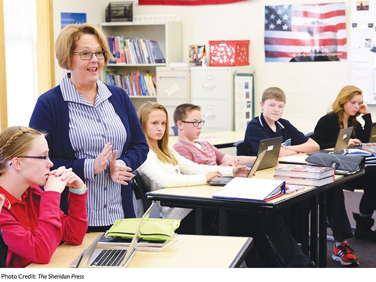 A Sheridan school teacher in front of Junior High School students using laptops.