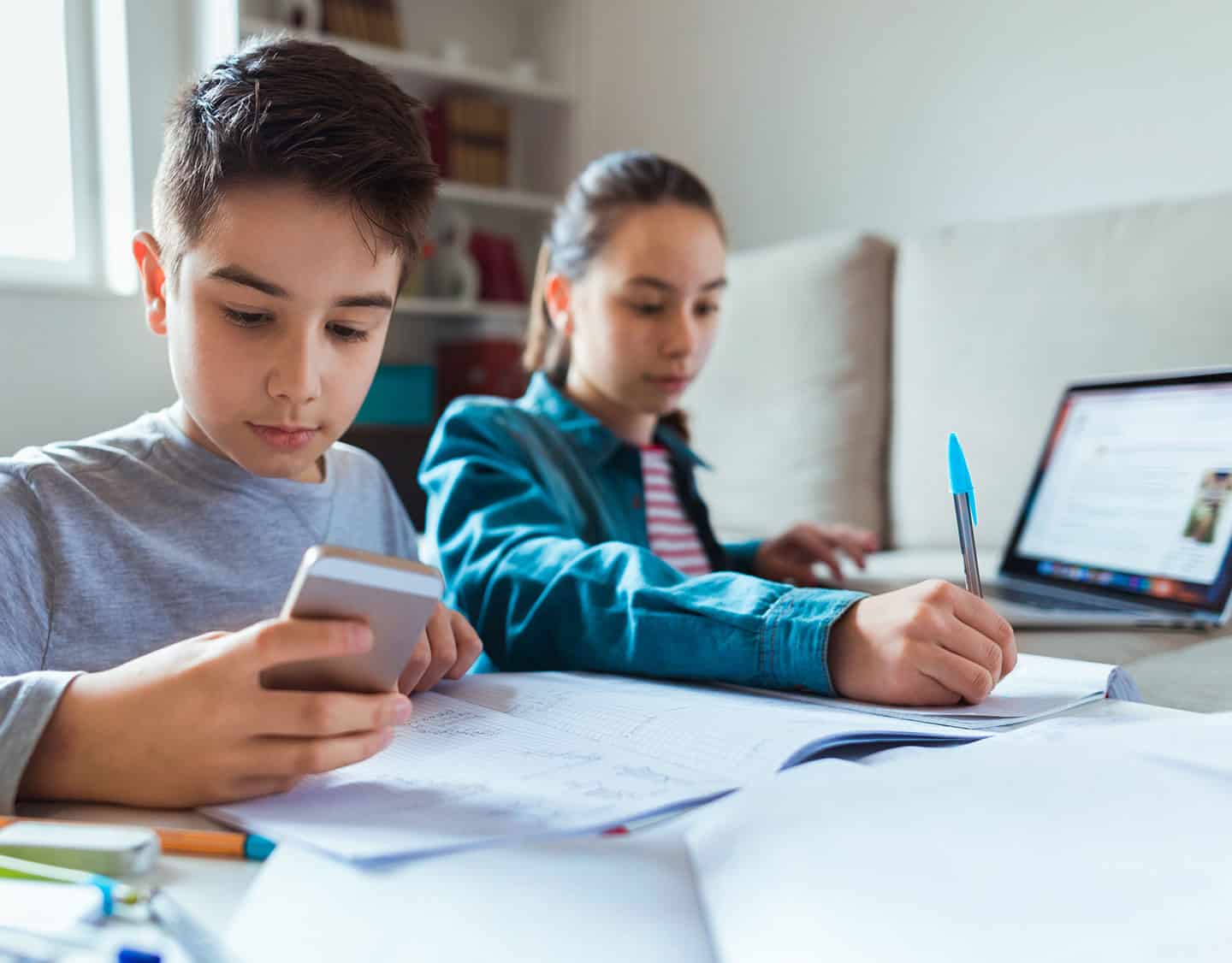 Two students doing homework on their devices at home