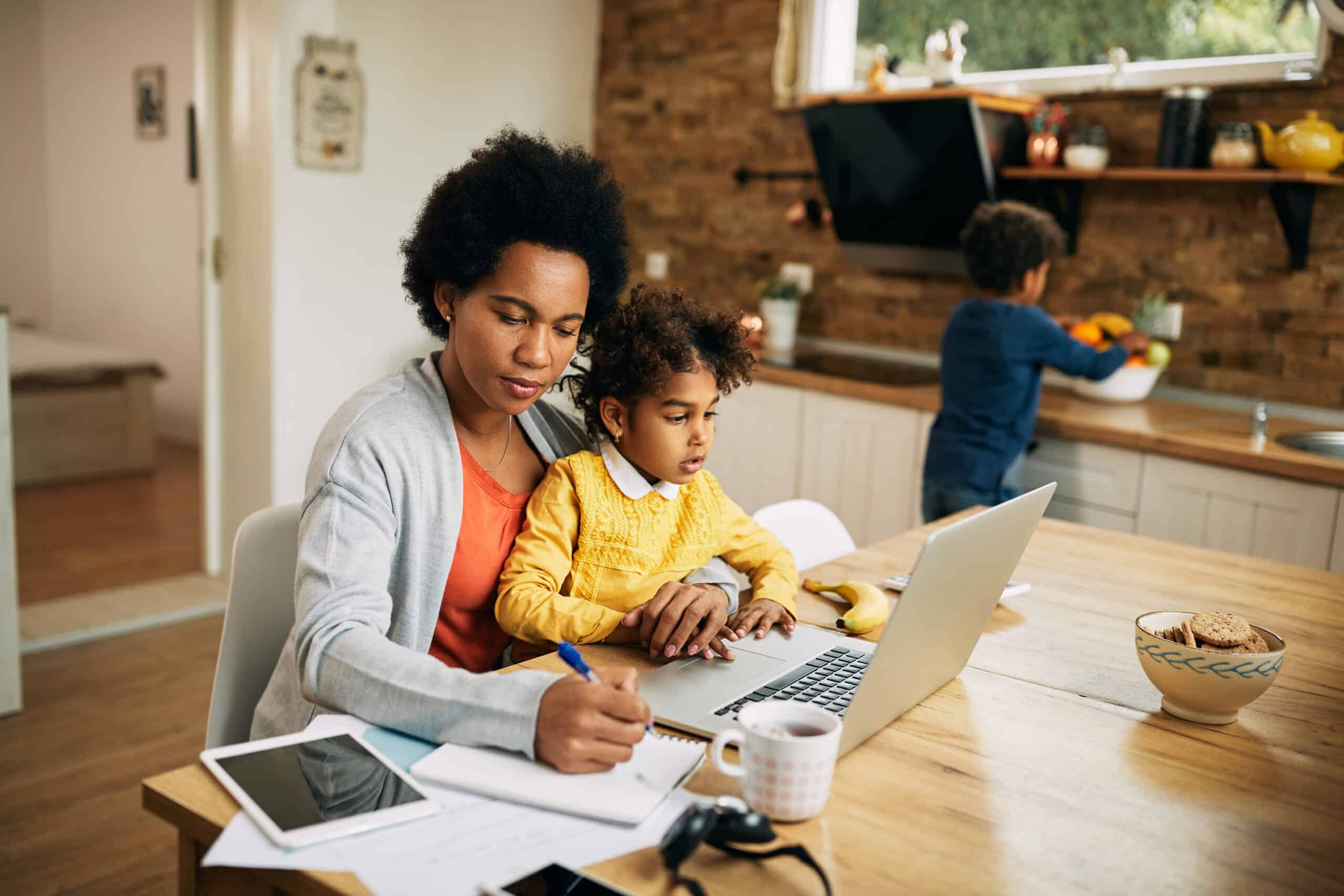mother sitting in chair with child in lap doing work with laptop