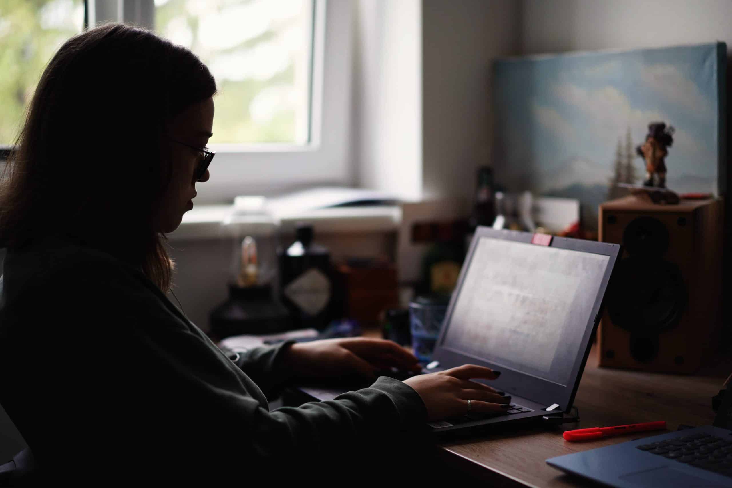 Student homeschooling in dark room