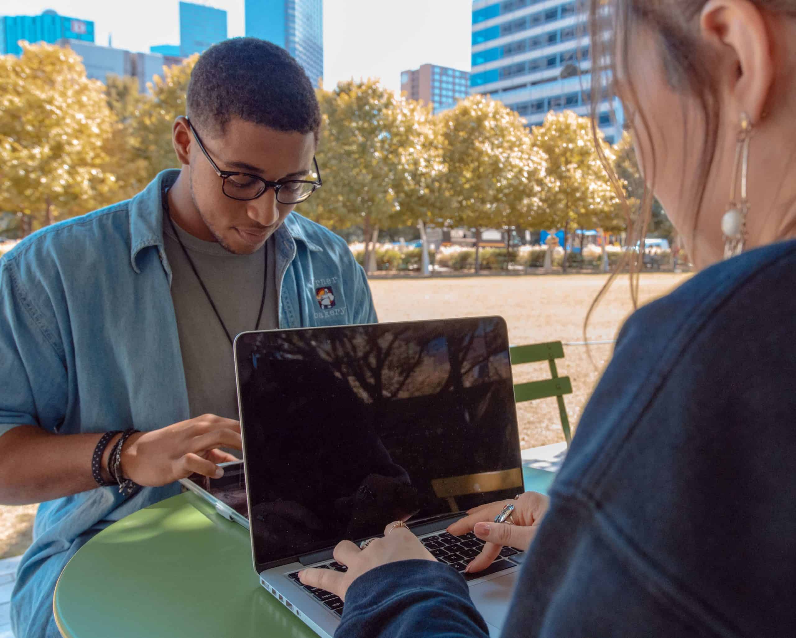 Two students using laptops outside